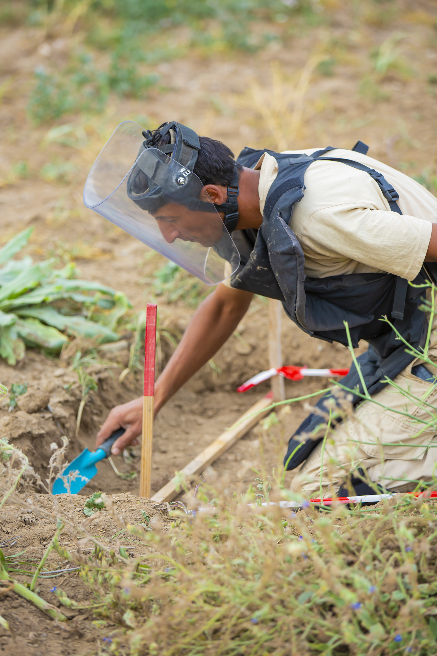 Deminer with a trowel in a demining lane